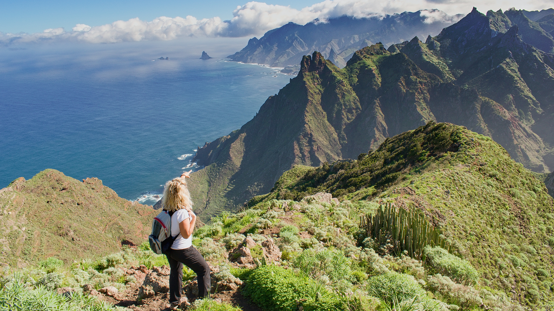 A young woman hiking on tall cliffs overlooking the sea