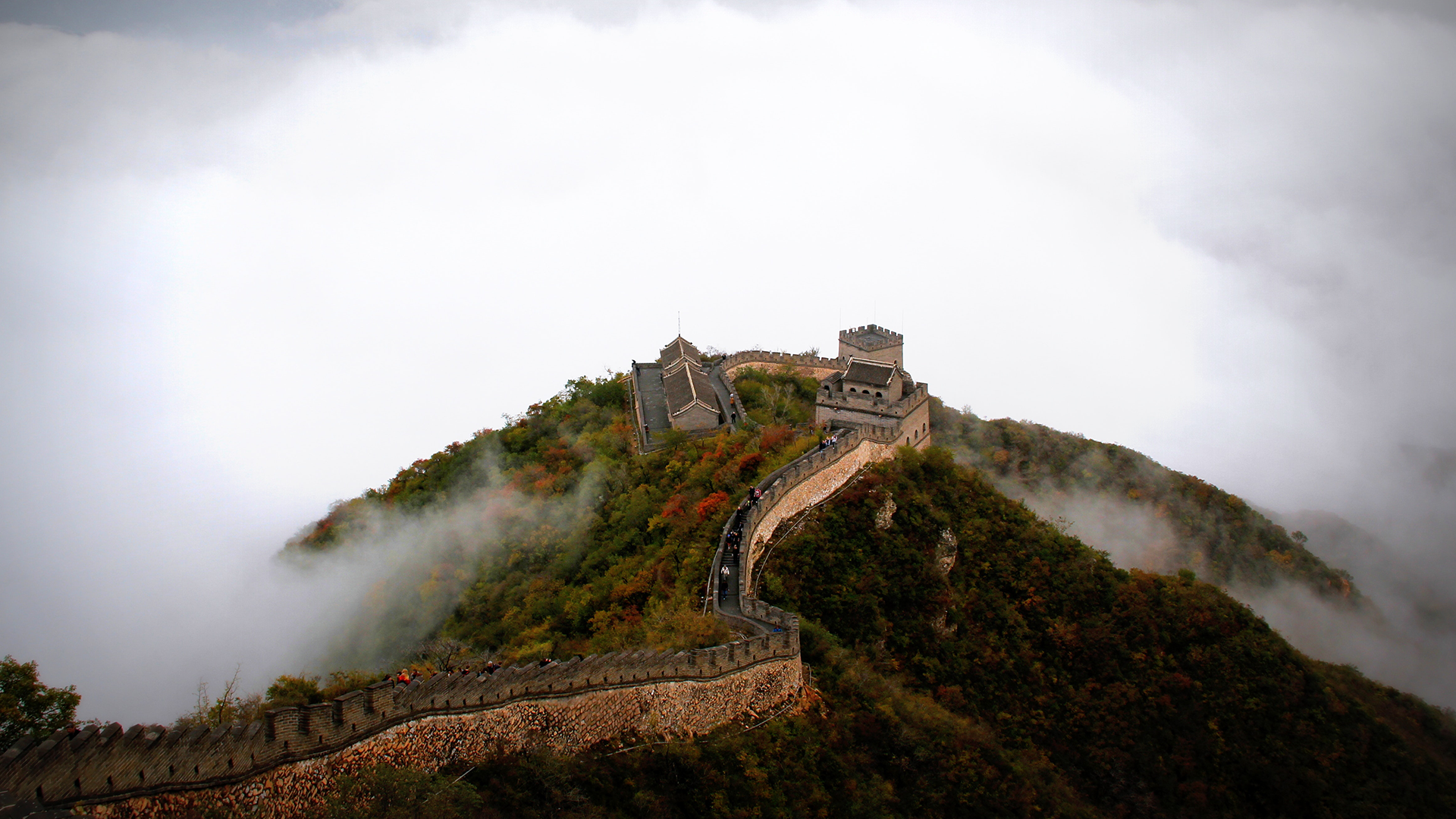 A photo of the Great Wall of China, on a mountain top above the clouds, taken from above