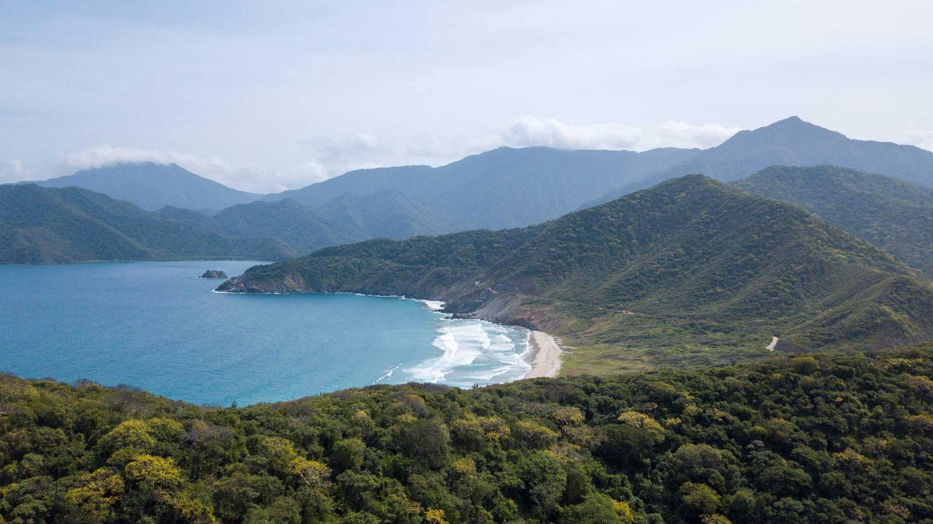 Aerial view of a beautiful beach surrounded by tall hills in Colombia