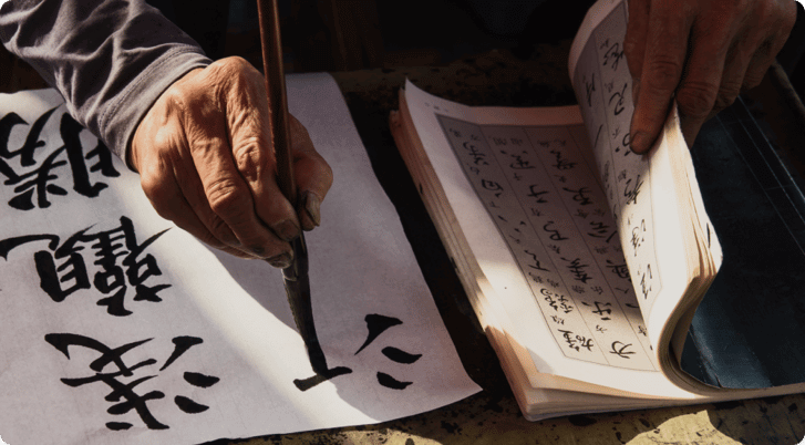 A person writing in Mandarin Chinese on a piece of paper